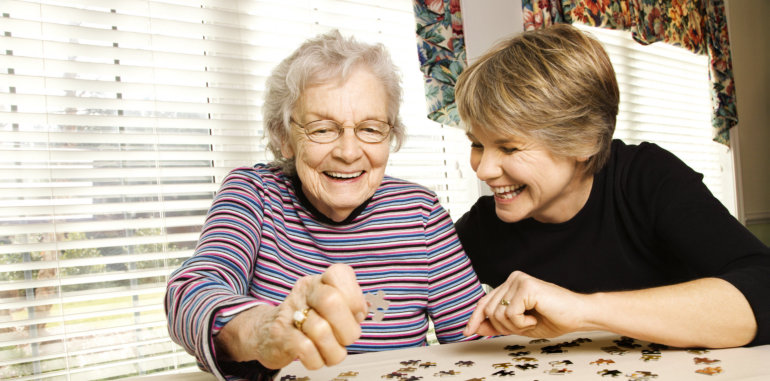 caregiver and elderly woman playing puzzle