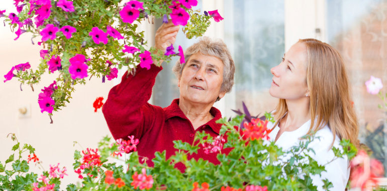 caregiver and elderly woman watching flowers