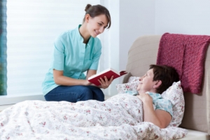 nurse reading story to an elderly woman